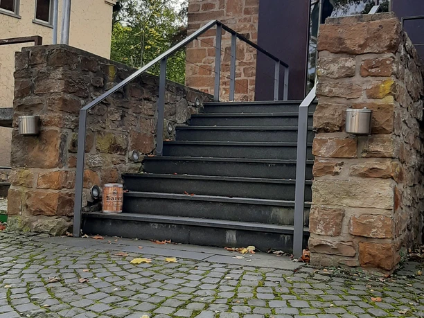 Eingangsbereich von Barre's Brauwelt mit steinerner Treppe, flankiert von historischen Mauern.