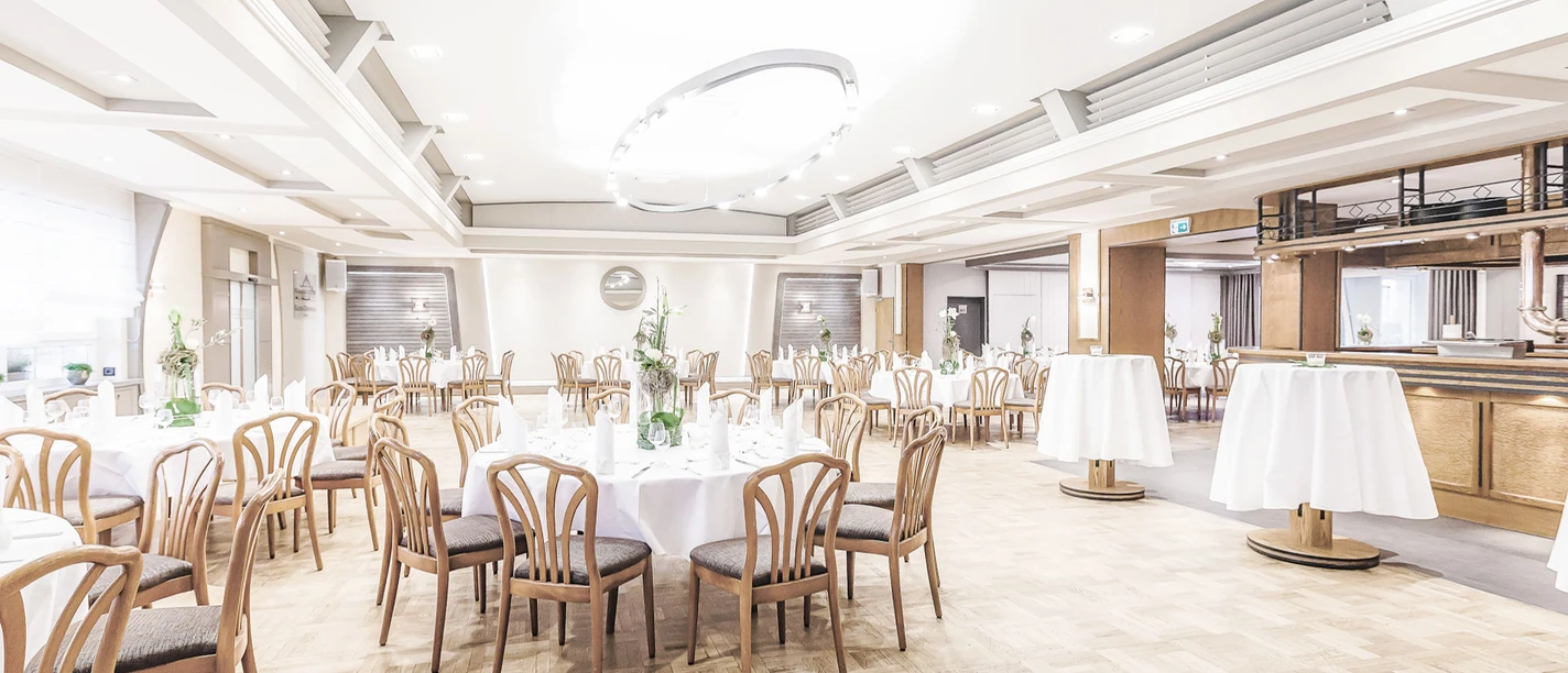 Gasthaus Kaiser-Dorfkrug Eleganter Veranstaltungsraum mit runden Tischarrangements, Holzstühlen und festlicher Beleuchtung.