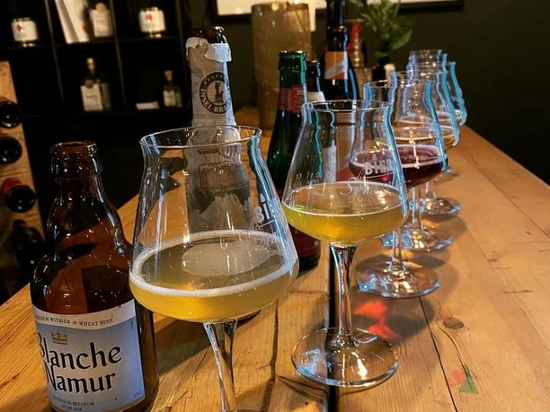 Fotos Lu´s Box.jpg Verschiedene Biersorten in Gläsern und Flaschen auf einem Holztisch, begleitet von Dekoration im Hintergrund.