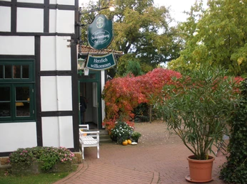 Gasthaus Schulenburg Historisches Fachwerkhaus mit begrüntem Eingang, roten Herbstblättern und einladender Beschilderung.