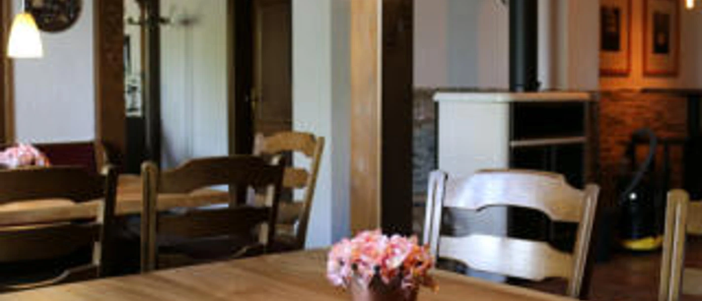 Gasthauswinkelhausen Hille Rustikales Gasthaus mit Holzmöbeln, Holzofen und warmem Licht; helle, einladende Atmosphäre.