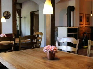 Gasthauswinkelhausen Hille Rustikales Gasthaus mit Holzmöbeln, Holzofen und warmem Licht; helle, einladende Atmosphäre.