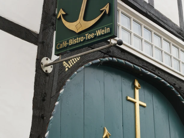 Anker Villa.JPG Fachwerkhaus mit Schild "AnkerVilla" und goldfarbenen Anker-Elementen vor blauen Holztüren.