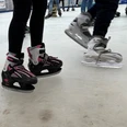 Schlittschuhläufer mit pinken und grauen Schlittschuhen gleiten über eine Eisbahn.