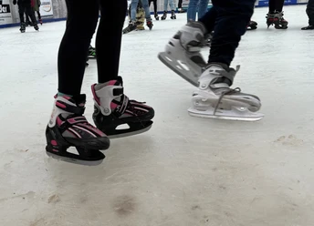 Schlittschuhe Schlittschuhläufer mit pinken und grauen Schlittschuhen gleiten über eine Eisbahn.