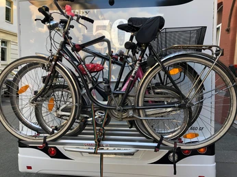 WoMo und Rad Zwei Fahrräder auf einem Fahrradträger sind an der Rückseite eines geparkten Wohnmobils befestigt.
