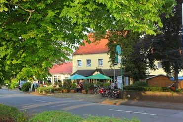 Hotel und Restaurant im Loh Espelkamp.jpg Hotel und Restaurant mit bunten Sonnenschirmen, umgeben von Bäumen, liegt an einer ruhigen Straße.