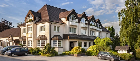 Hotel-Restaurant Kahle Wart.png Ein großes Hotel-Restaurant mit markanter Dacharchitektur und grüner Umgebung unter blauem Himmel.