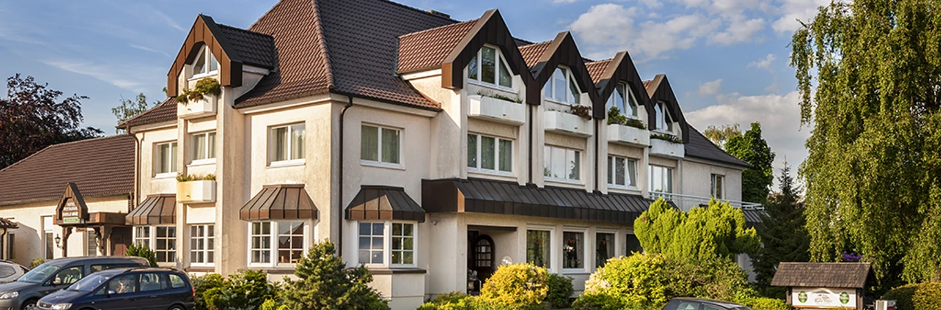 Hotel-Restaurant Kahle Wart.png Ein großes Hotel-Restaurant mit markanter Dacharchitektur und grüner Umgebung unter blauem Himmel.
