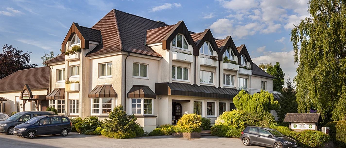 Hotel-Restaurant Kahle Wart.png Ein großes Hotel-Restaurant mit markanter Dacharchitektur und grüner Umgebung unter blauem Himmel.
