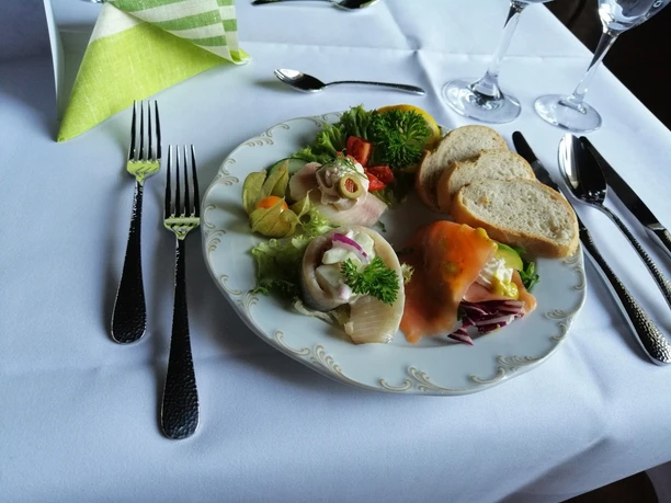 Ein liebevoll gedeckter Tisch mit Teller voller Fischvorspeisen, Brotscheiben und Salatgarnitur.