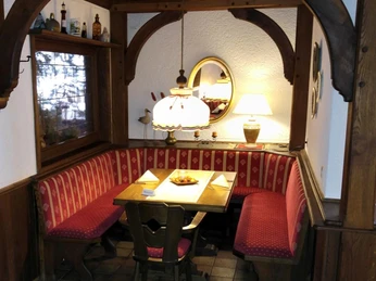 Hotel-Restaurant Lindenhof Eine gemütliche Sitzecke im Hotel-Restaurant Lindenhof mit roter Polsterbank und hölzernem Tisch.