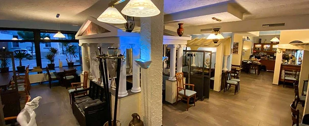 Ilias Taverne_Luebbecke.jpg Innenraum einer griechischen Taverne mit Säulen, warmem Licht und traditionellen Dekorationen.