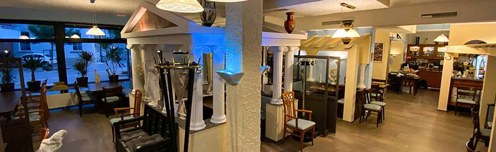 Ilias Taverne_Luebbecke.jpg Innenraum einer griechischen Taverne mit Säulen, warmem Licht und traditionellen Dekorationen.