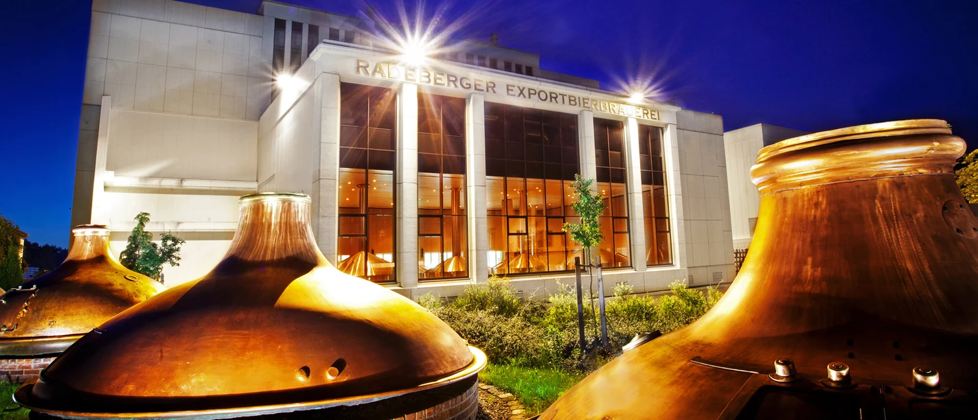 Radeberger Brauerei Radeberger Brauerei bei Nacht mit beleuchteten Kupferkesseln und beleuchtetem Gebäude im Hintergrund.