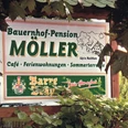Landcafé Up n Roithen_PrOldendorf.jpg Schild der Bauernhof-Pension Möller mit Café, Ferienwohnungen und Sommerterrasse, umrahmt von Blättern.