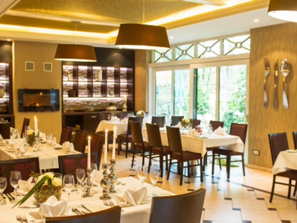 Krug zum grünen Kranze Ein eleganter Speiseraum mit gedeckten Tischen, stimmungsvoller Beleuchtung und großen Fenstern.