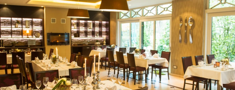 Krug zum grünen Kranze Ein eleganter Speiseraum mit gedeckten Tischen, stimmungsvoller Beleuchtung und großen Fenstern.