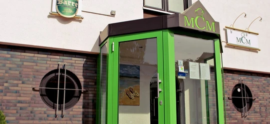 MCM Restaurant_Espelkamp.jpg Eingang des MCM Restaurants mit auffällig grünem Vordach und runden Fenstern an der Ziegelfassade.