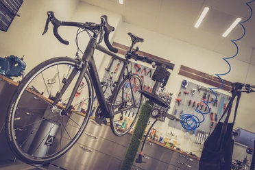 Ein modernes Fahrrad steht auf einer Montagerampe in einer gut ausgestatteten Fahrradwerkstatt.