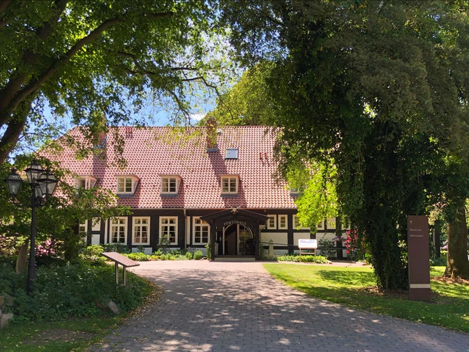 Ein Fachwerkhotel im Grünen, umgeben von Bäumen, mit gepflastertem Weg zum Eingang.