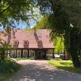 Hotel Forsthaus Heiligenberg Ein Fachwerkhotel im Grünen, umgeben von Bäumen, mit gepflastertem Weg zum Eingang.