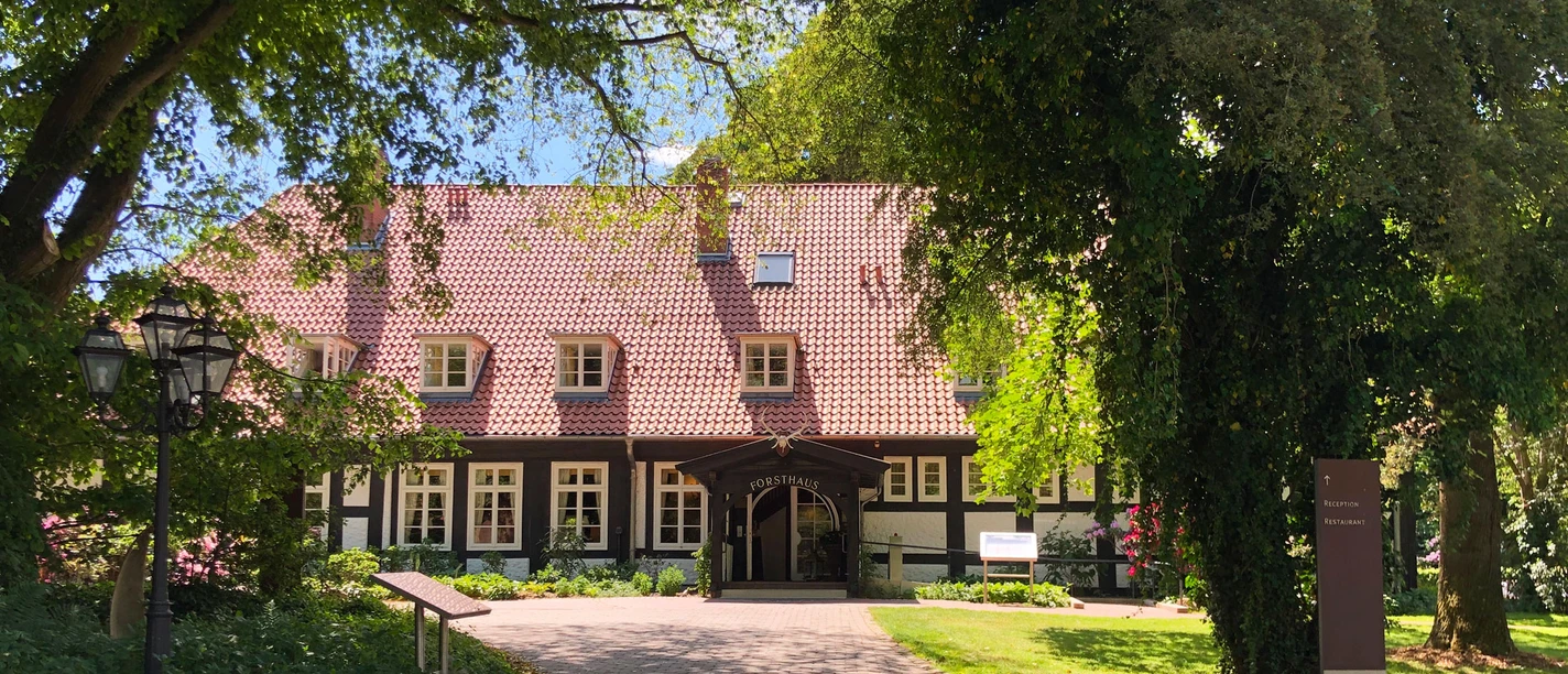 Hotel Forsthaus Heiligenberg Ein Fachwerkhotel im Grünen, umgeben von Bäumen, mit gepflastertem Weg zum Eingang.