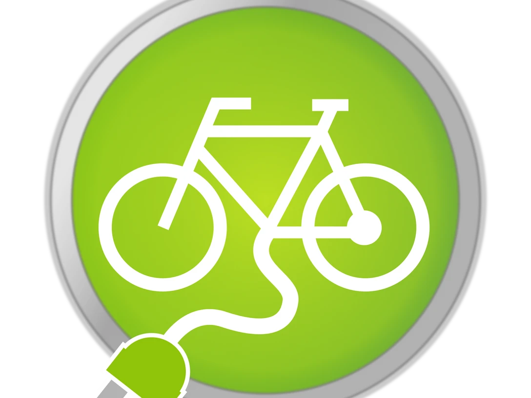 pixabay-e-bike-4259439.png Symbol für eine Fahrradladestation: Ein weißes Fahrrad mit Stecker auf grünem Hintergrund in einem Kreis.