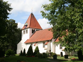 Kirche Heimsen Eine weiße Kirche mit rotem Ziegeldach und Turm, umgeben von grünen Bäumen und gepflegtem Rasen.