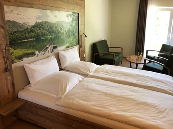 Zimmer-Weser-Suits Ein modern eingerichtetes Hotelzimmer mit Holzdetails, einem Doppelbett, kleinen Tisch und zwei Sesseln.A modern hotel room with wooden details, a double bed, small table and two armchairs.Et moderne hotelværelse med trædetaljer, en dobbeltseng, et lille bord og to lænestole.Een moderne hotelkamer met houten details, een tweepersoonsbed, kleine tafel en twee fauteuils.