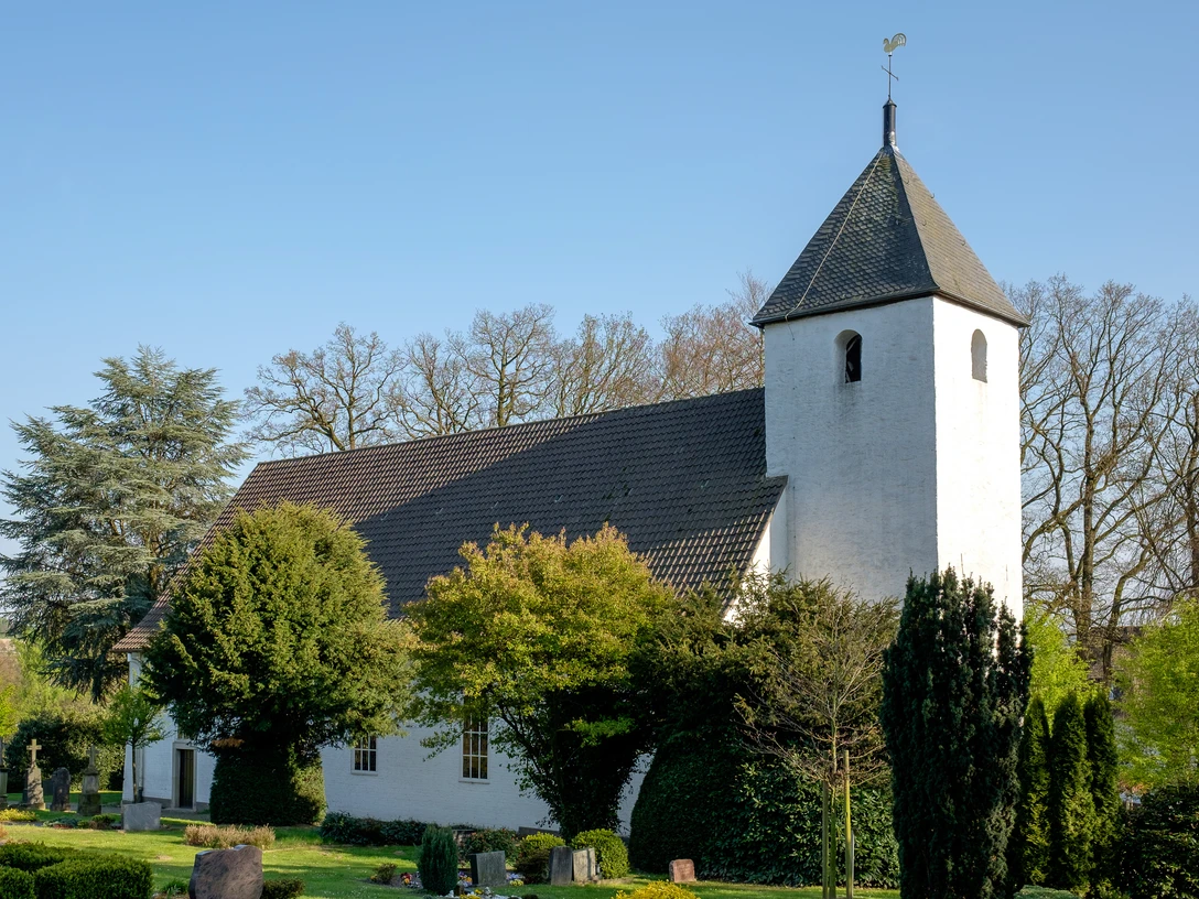 Autobahnkirche Exter Autobahnkirche Exter, weißer Bau mit dunklem Tonnendach, umgeben von grünen Bäumen und Sträuchern.