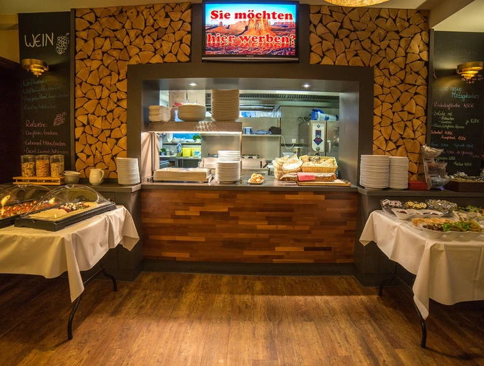 POI Schneiders am Brunnen (2 von 9) (1).jpg Restaurantbuffet mit Holzwänden, gedeckten Tischen und Einblick in die gut beleuchtete Küche.