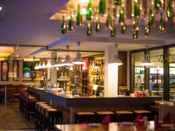 POI Schneiders am Brunnen (6 von 9)(1).jpg Ein modernes Restaurant mit stilvoller Bar, intensiver Beleuchtung und dekorativen Elementen.