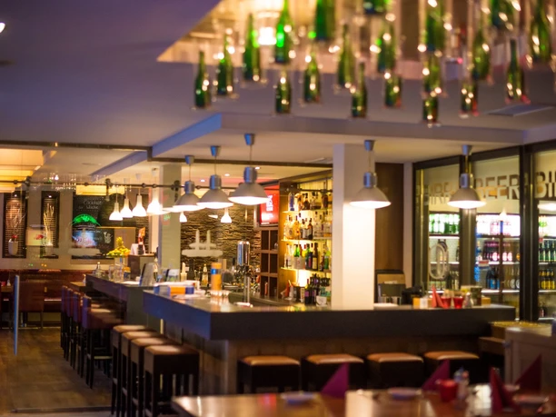 POI Schneiders am Brunnen (6 von 9)(1).jpg Ein modernes Restaurant mit stilvoller Bar, intensiver Beleuchtung und dekorativen Elementen.