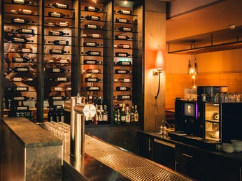 POI 4 Steakhouse.jpg Eine stilvolle Bar mit zahlreichen Weinflaschen an der Wand, moderner Theke und dezenter Beleuchtung.