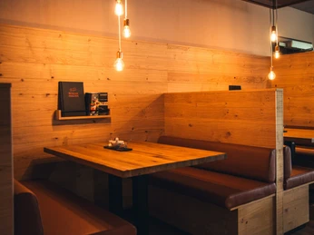 POI 5 3Steakhouse.jpg Holzverkleidete Restaurantkabine mit Lederbänken und sanfter Beleuchtung durch hängende Lampen.