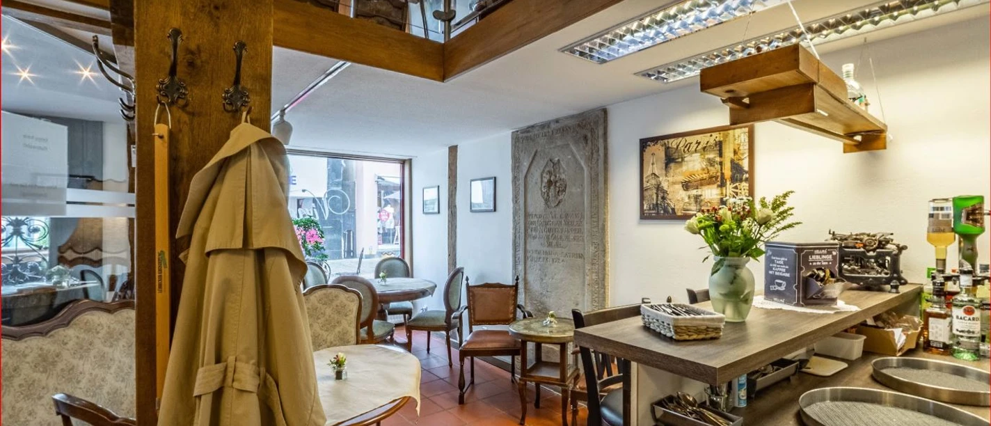 VinesCafe_Luebbecke.JPG Gemütliches Café-Interieur mit Holzelementen, antikem Dekor und Blumen auf Tischen, lädt zum Verweilen ein.