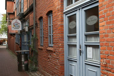 Historic brick façade of a hotel with blue windows and doors in a narrow alley.