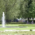Radfahrer genießen den großzügigen Schloss- und Auenpark mit sprudelndem Brunnen und viel Grün.