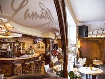 Gemütliches Café mit Holzeinrichtung und Barhockern, warm beleuchtet, mit Orchideen am Tisch.