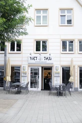 ViethThai.jpg Fassade eines vietnamesischen Restaurants "Viet Thai" mit Außensitzbereich und geöffneten Sonnenschirmen.