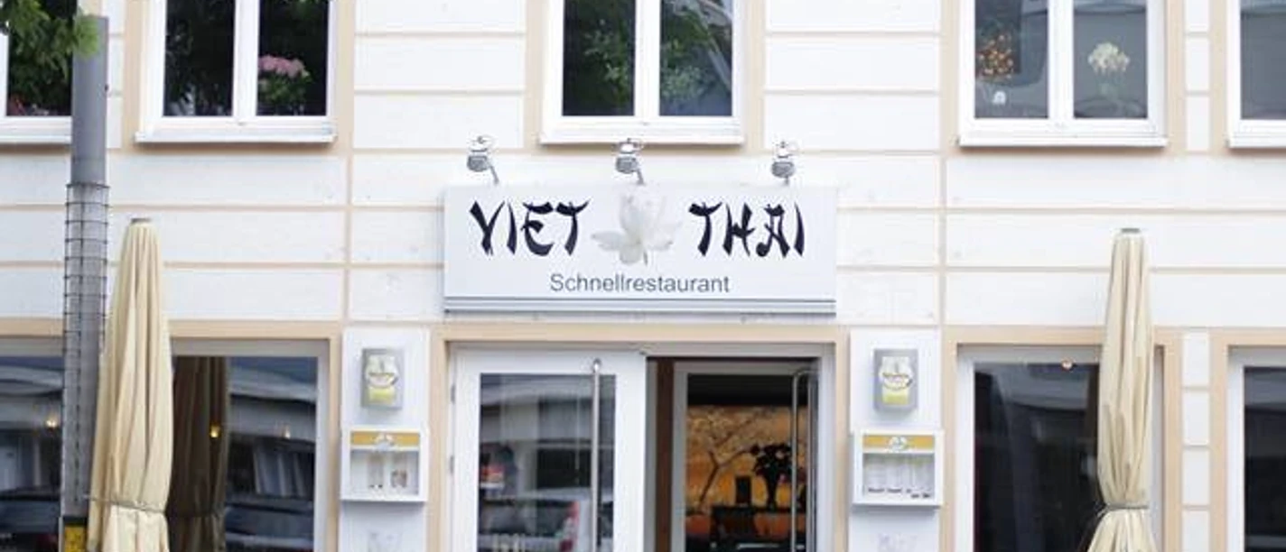 ViethThai.jpg Fassade eines vietnamesischen Restaurants "Viet Thai" mit Außensitzbereich und geöffneten Sonnenschirmen.
