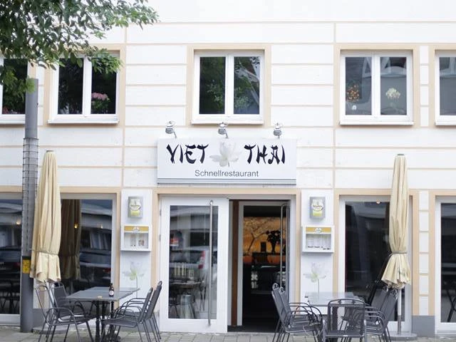 ViethThai.jpg Fassade eines vietnamesischen Restaurants "Viet Thai" mit Außensitzbereich und geöffneten Sonnenschirmen.