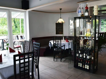 filippo2.jpg Elegantes Restaurant mit Glasvitrine voller Weinflaschen, gedeckten Tischen und gepflegtem Ambiente.