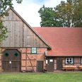 Heimatzentrum Senne - Manfred Funke.jpg Eine traditionelle Backstein-Scheune mit Satteldach und Holztor auf einer grünen Wiese.