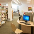 Bibliothek_Rheda_Internet.jpg Bibliothek mit Bücherregalen, Computertischen und Lesestühlen in einem modernen und einladenden Raum.