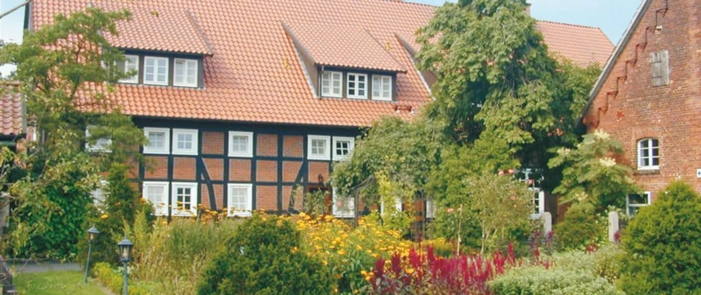 Landhotel_Marburg.jpg Fachwerkhaus mit rotem Ziegeldach, umgeben von üppigem Garten mit bunten Blumen und Sträuchern.
