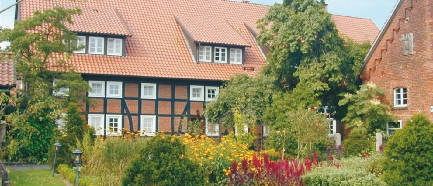 Landhotel_Marburg.jpg Fachwerkhaus mit rotem Ziegeldach, umgeben von üppigem Garten mit bunten Blumen und Sträuchern.