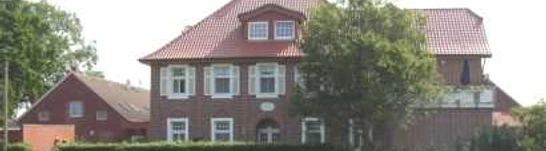 Biermann_1.jpg Backsteinhaus mit rotem Dach in ländlicher Umgebung, üppiges Grün und blauer Himmel im Hintergrund.