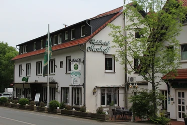 Balkes Morhoff Waldhotel Morhoff in ländlicher Umgebung, umgeben von Bäumen, mit rotem Dach und weißen Wänden.